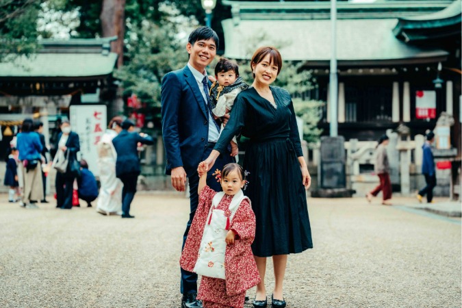 レタッチ前:背景に通行人が写り込んでいる神社での家族写真